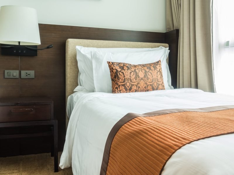 White pillow on bed decoration in bedroom interior with table light lamp